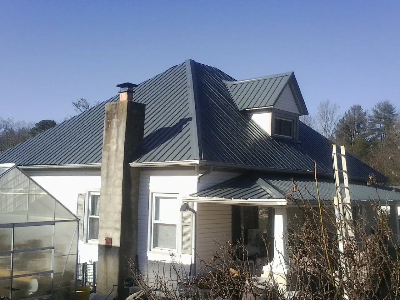 Dark blue standing seam metal roof on a white farmhouse with dormer — Slate & Tile Roof Repair by Roofing Brothers in Trenton