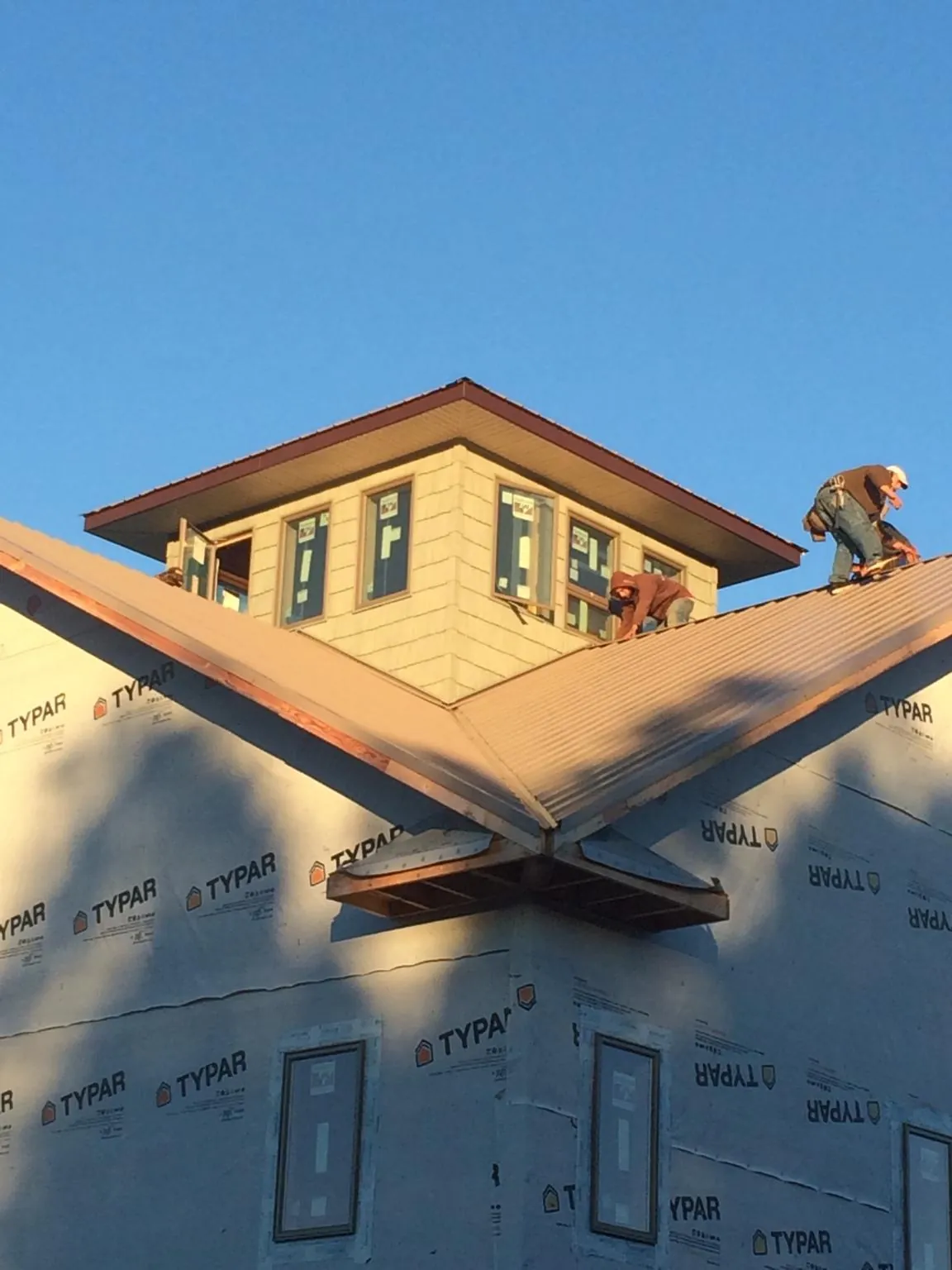 Roofers working around a rooftop cupola on a new metal roof at sunset — Roof Waterproofing in Trenton by Roofing Brothers